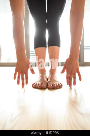 Unrecognizable woman exercising at home, stretching legs and arm Stock Photo