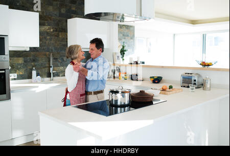 Senior couple in the kitchen cooking and dancing together. Stock Photo