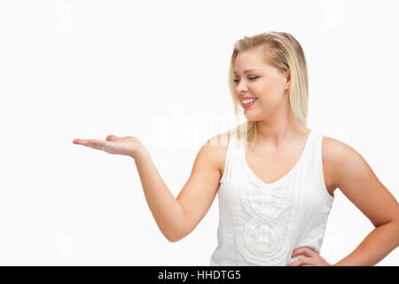 Smiling woman placing her hand palm up against a white background Stock Photo