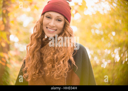 Portrait smiling woman in stocking cap under autumn trees Stock Photo