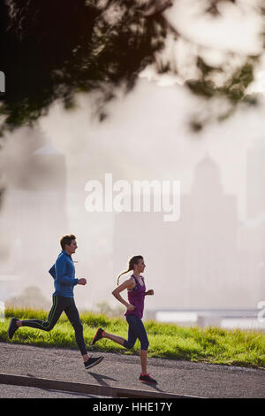 Runner couple running on sunny urban sidewalk Stock Photo