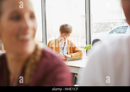 Woman with headphones using digital tablet at cafe window Stock Photo