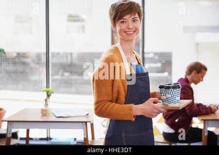 Portrait confident female cafe owner serving coffee on tray in cafe Stock Photo