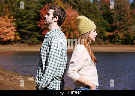 Two people, a couple back to back standing by a lake Stock Photo