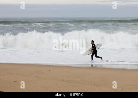 Surfer exiting the water beach in Donostia beach (Basque country, Spain). Stock Photo