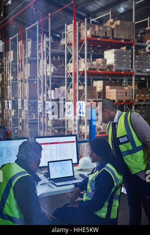 Managers at laptop and computers in distribution warehouse Stock Photo