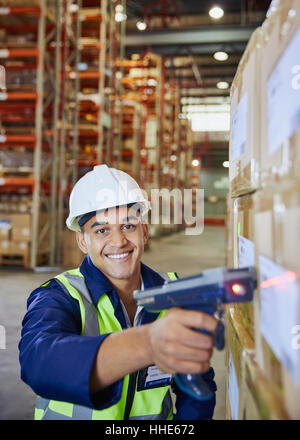 Portrait smiling worker using scanner scanning boxes in distribution warehouse Stock Photo
