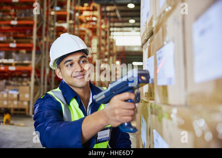 Worker with scanner scanning boxes in distribution warehouse Stock Photo