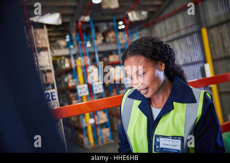 Smiling female worker looking down in distribution warehouse Stock Photo