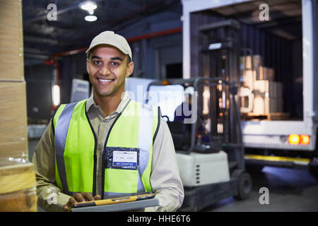 Portrait smiling worker in front of forklift and truck at distribution warehouse loading dock Stock Photo