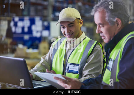 Workers with clipboard and laptop working in distribution warehouse Stock Photo