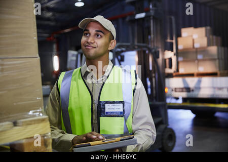 Worker with clipboard checking boxes in distribution warehouse Stock Photo