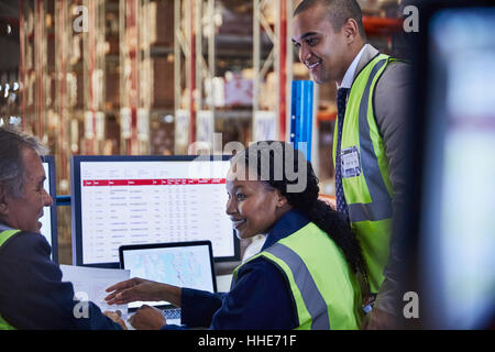 Managers meeting working at computer and laptop in distribution warehouse Stock Photo