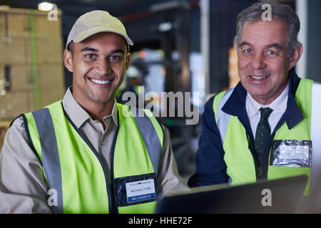 Portrait smiling manager and worker using laptop in distribution warehouse Stock Photo