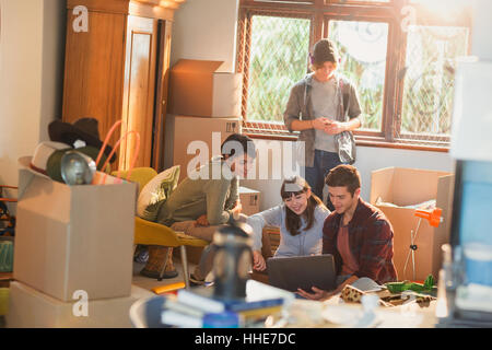 Young couples roommates using laptop surrounded by moving boxes Stock Photo