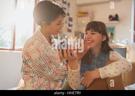 Young women friends applying makeup Stock Photo