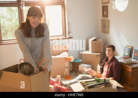Portrait smiling young couple unpacking moving boxes in apartment Stock Photo