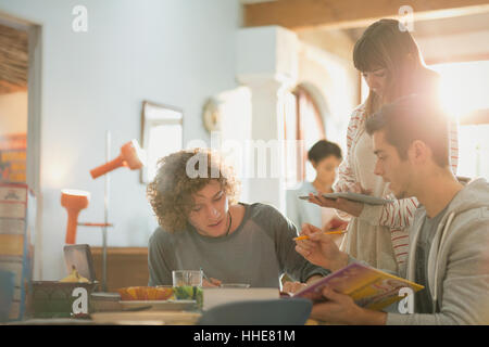 Young friends college students studying using book and digital tablet at table Stock Photo
