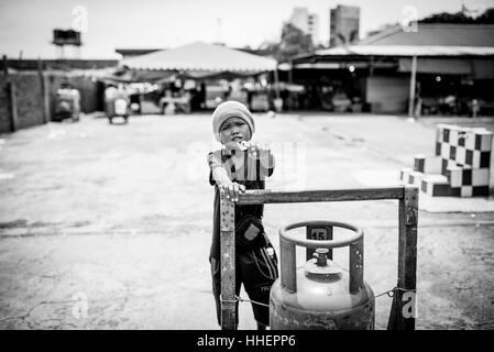 A young boy points a gun (assumed to be a toy) in the direction of the photographer: Kota Kinabalu, Malaysia on the island of Borneo. Stock Photo
