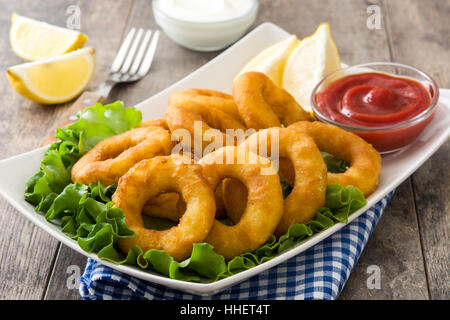 Fried calamari rings with lettuce and ketchup on wooden background Stock Photo