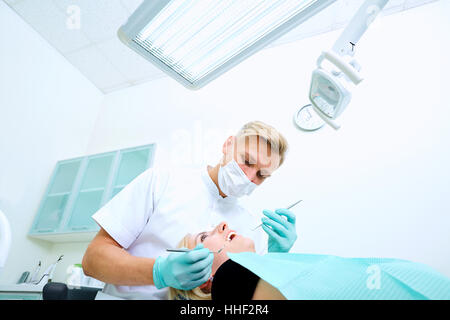 The dentist treats a patient  mask in  dental office Stock Photo
