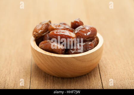 date palm dried fruit in wooden bowl on wood background Stock Photo