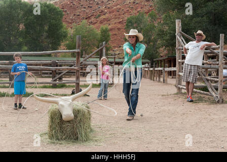 Roping practice at the Lazy L&B dude ranch in Dubois, Wyoming: wrangler lassos a hay bale cow while children await their turn. Stock Photo