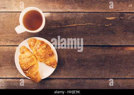 croissant with cup of tea on wooden table. copy space Stock Photo