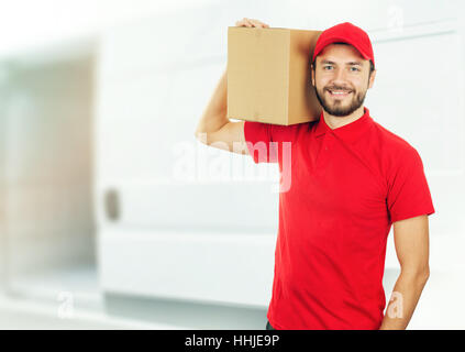 happy delivery man with box on shoulder in front of a truck Stock Photo