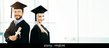 graduation - happy students wearing gown and cap. copy space Stock Photo