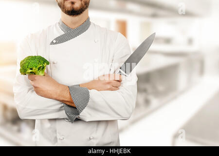 chef in restaurant kitchen with broccoli and knife in hands Stock Photo