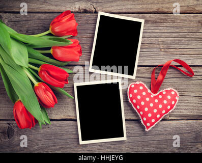 Red tulips, blank photo frames and heart over wooden table. Valentines day background. Top view with copy space. Retro toned Stock Photo