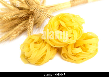 Pasta tagliatelle in a nest and spikelets wheat isolated on white background. Stock Photo