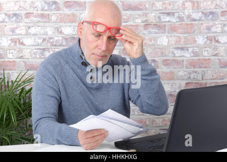 handsome mature man opening letter envelope in his office Stock Photo