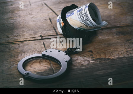 Handcuffs with money on wooden background. US currency Stock Photo