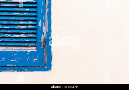 Blue closed old stained wooden window on a white wall. Stock Photo