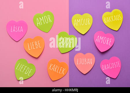 some heart-shaped sticky notes of different colors with the word love written in different languages, such as Spanish, Portuguese, Italian, French, Po Stock Photo