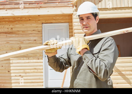 Worker carrying wood at construction site during building construction Stock Photo