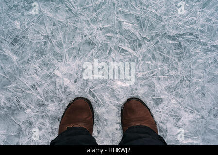 Legs traveler in shoes standing on thin ice and a beautiful ice. Stock Photo
