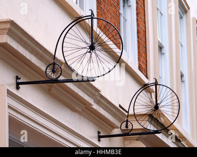 Mini Penny Farthing bicycles mounted on wall in Soho, London Stock Photo