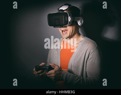 Man wearing virtual reality goggles. Guy playing video game with gamepad Stock Photo