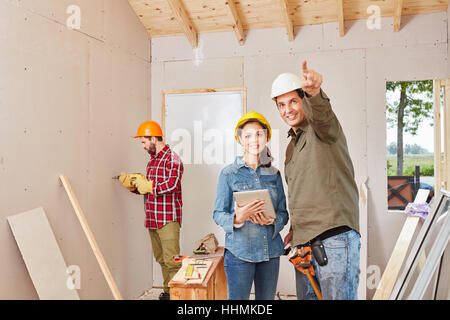 Craftsman's team working with tablet computer and cooperating on new building Stock Photo