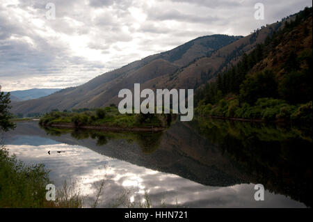 Calm portion of the Salmon River showing the reflection of the Sawtooth Mountains and cloudy sky in a valley leading to Shoup Stock Photo