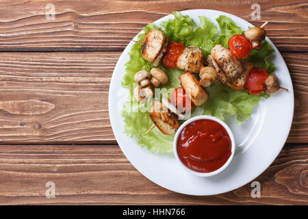 two fried chicken meat with vegetables on wooden skewers on a plate sauce. top view Stock Photo