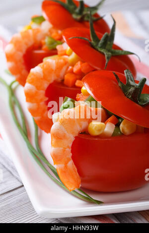 Appetizer of fresh tomatoes stuffed with shrimp and vegetables closeup. vertical. Stock Photo