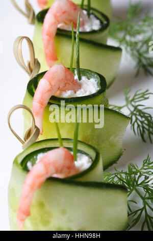 appetizer buffet: cucumber rolls with shrimp and cheese on white plate vertical macro. Stock Photo