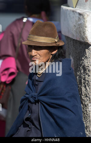 August 5, 2016 Otavalo, Ecuador: an elderly indigenous woman sitting in the sun outdoors dressed traditionally Stock Photo