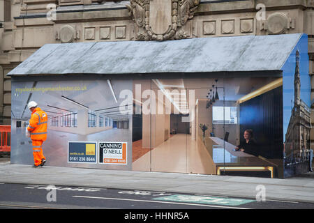 Workman in hi-vis clothing walking past an interior office scene painted on Innovative Hoarding, painted timber framework.  A unusual design illusion for a building entrance to a internal construction site in Royal Exchange Building, Market Street,  Manchester, UK. Stock Photo