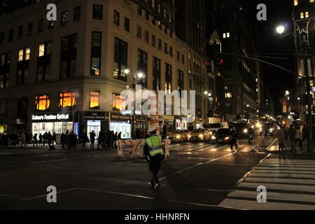 Police traffic officer in New York city with steam vapor being vented through orange and white stack in middle of a junction Stock Photo