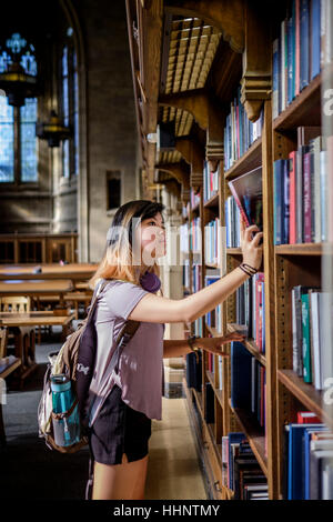 Chinese woman standing in library choosing book Stock Photo